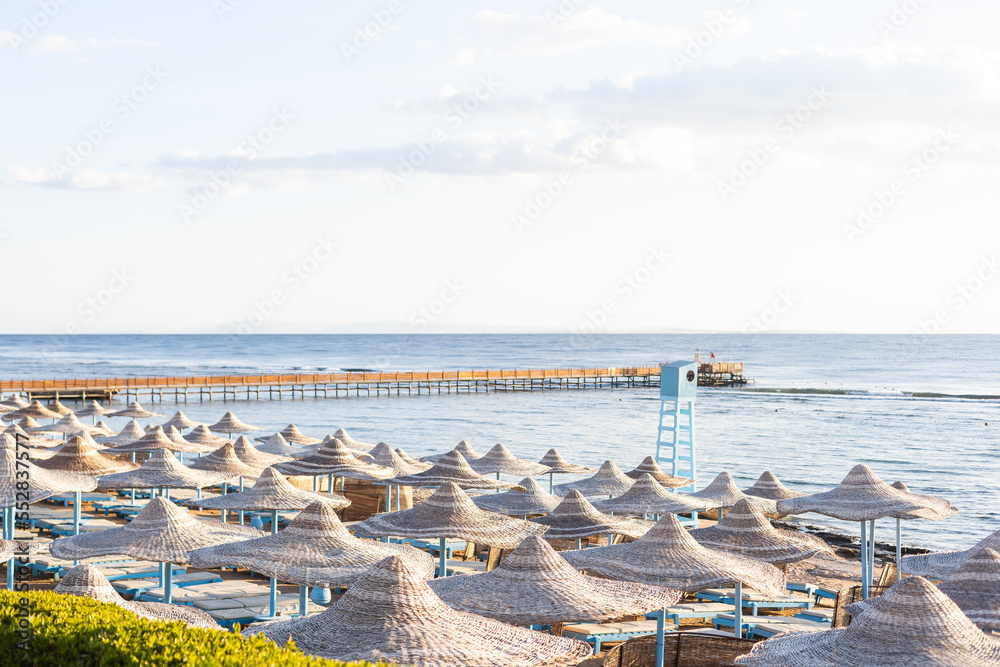 Mediterranean coast with sunbeds and straw sun umbrellas on the sandy beach