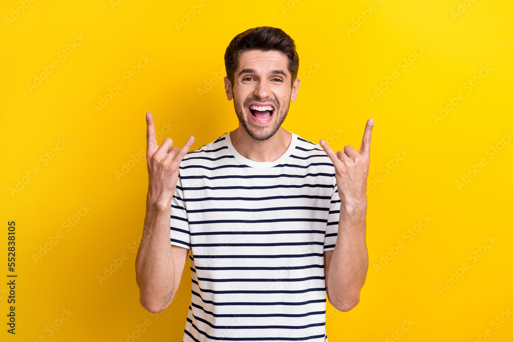 Portrait of carefree positive person arms demonstrate heavy metal symbol shout yell isolated on yellow color background Portrait of carefree positive person arms demonstrate heavy metal symbol shout yell isolated on yellow color background