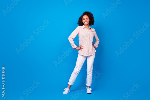 Full length portrait of pretty cheerful person put hands waist posing isolated on blue color background