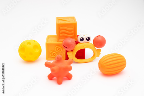 Three sensory balls in different warm colors, three silicone soft cubes and a crab-shaped rattle. Tactile toys for the development of babies from three months