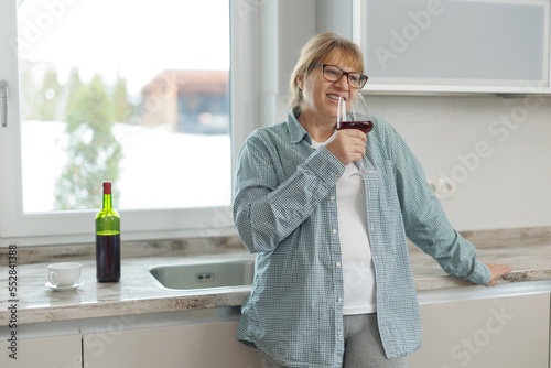 Woman drinking a glass of wine in a modern kitchen photo