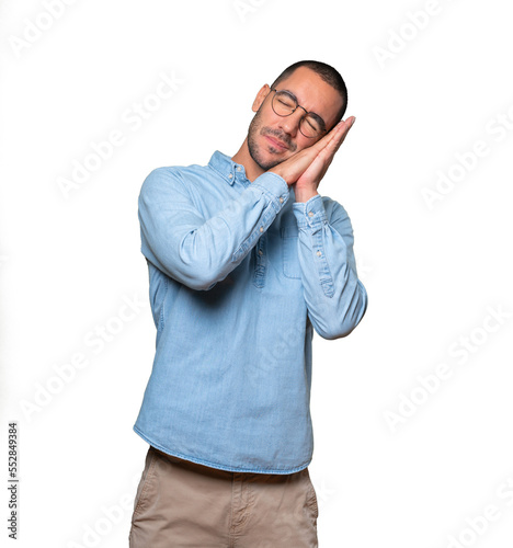 Relaxed young man making a gesture of sleep