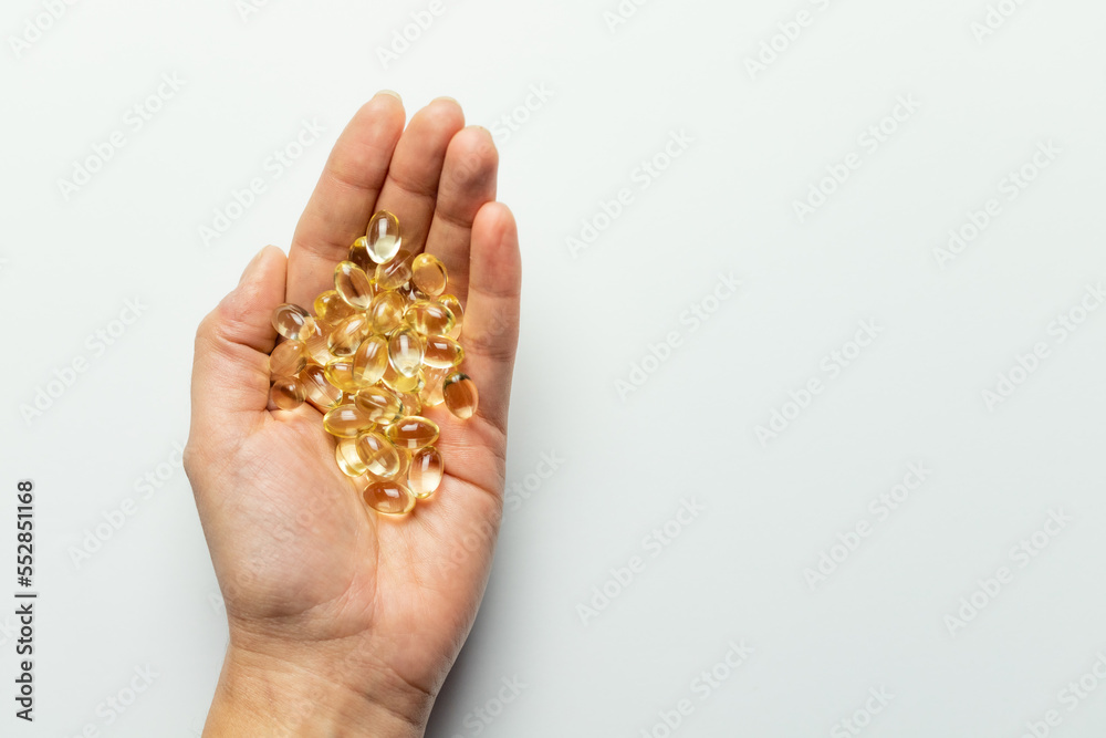 Fototapeta premium Vitamin D3 capsules on the hands. White background, space for text.