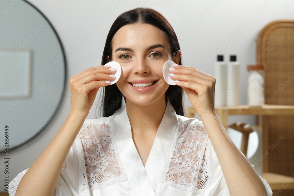 Young woman using cotton pads with micellar water indoors Young woman using cotton pads with micellar water indoors