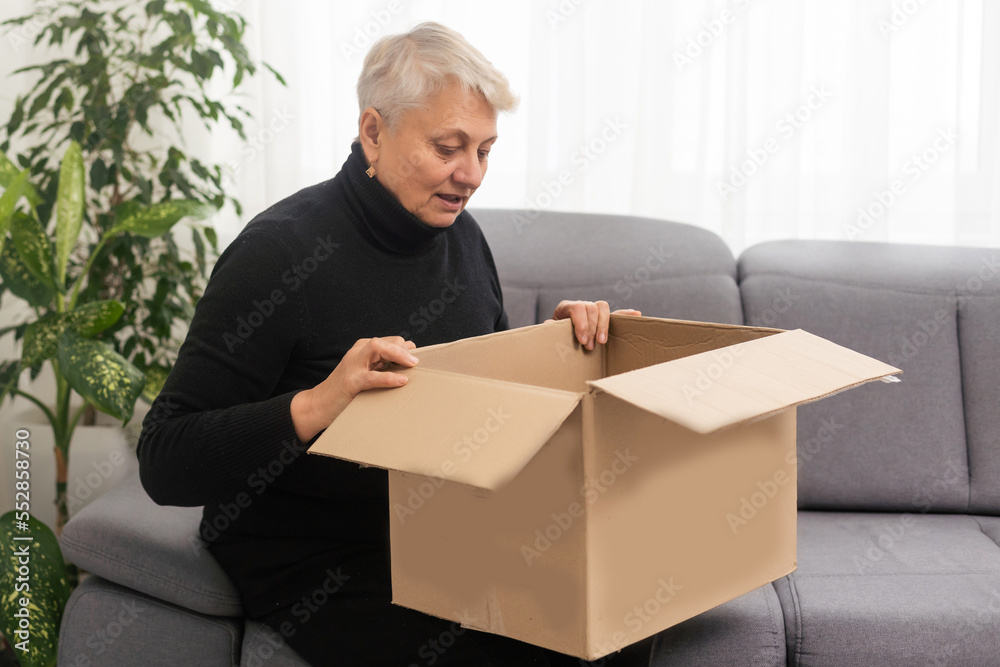 Elderly woman unpacking things in new house. opening cardboard box. Real estate, purchase concept Elderly woman unpacking things in new house. opening cardboard box. Real estate, purchase concept