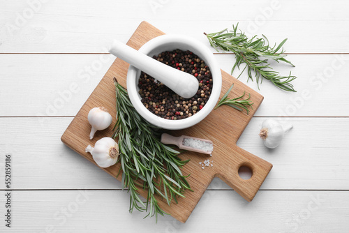 Flat lay composition with fresh green rosemary and mortar on white wooden table