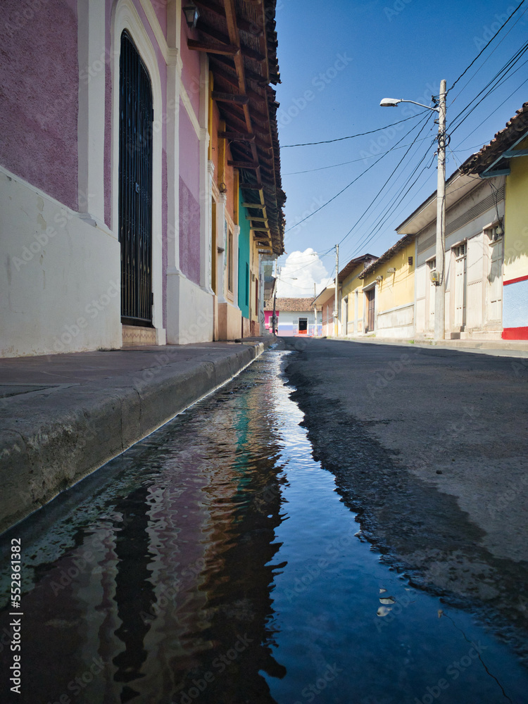 Street scene of Granada, Nicaragua. Old colonial houses in street with reflections in Water. Colonial houses street. Nicaragua city scene. Colorful colonial-style houses. Latin American city scene. 