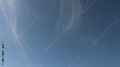 4K timelapse of light as feathers cirrus clouds moving in light blue sky photo