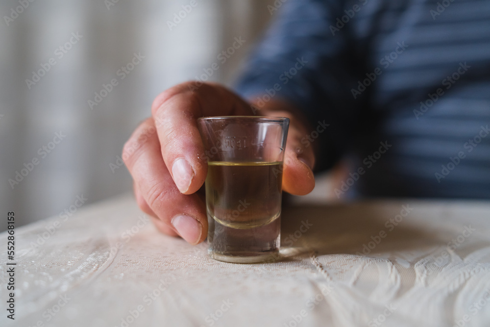 A close up of grandfathers hand holding a glass of rakija alcoholic drink A close up of grandfathers hand holding a glass of rakija alcoholic drink