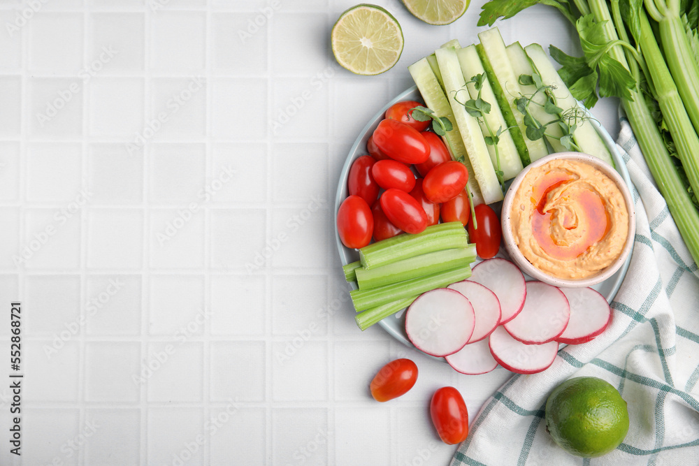 Plate with delicious hummus and fresh vegetables on white table, flat lay. Space for text Plate with delicious hummus and fresh vegetables on white table, flat lay. Space for text