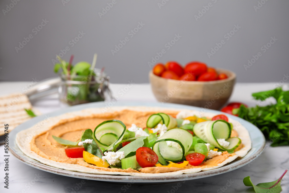 Tortilla with hummus and vegetables on table, closeup Tortilla with hummus and vegetables on table, closeup