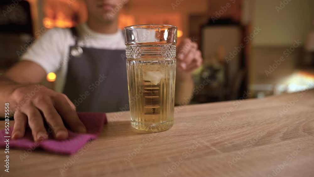 Cleanliness in pub. Professional bartender at counter wiping wooden surface with rag in bar Cleanliness in pub. Professional bartender at counter wiping wooden surface with rag in bar