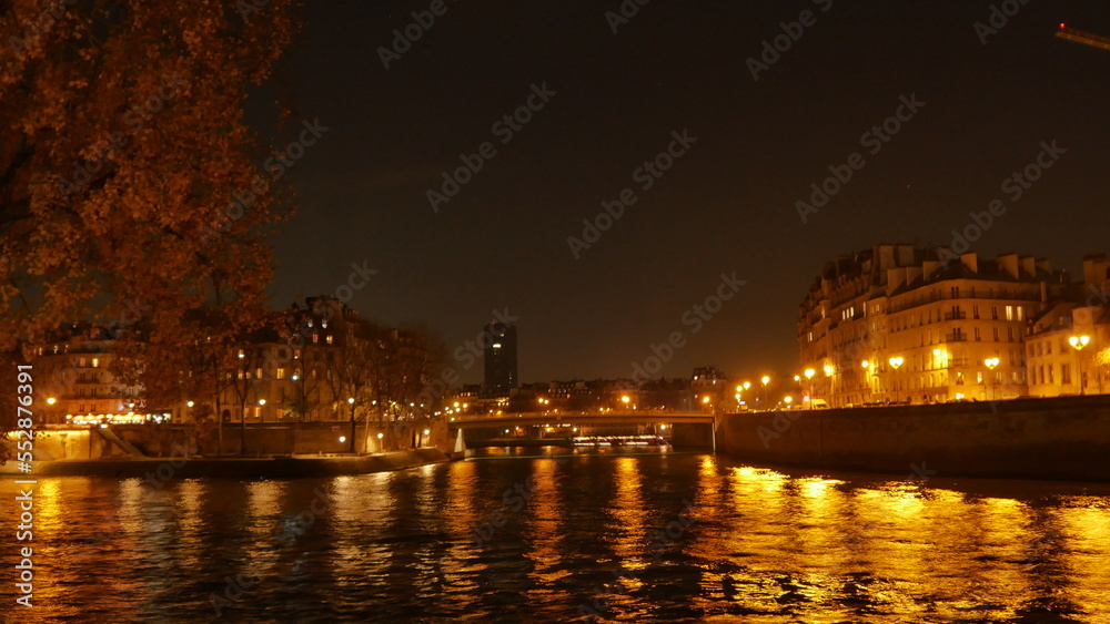 Promenade au bord de la Seine pendant une soirée, saison d'automne, sous un fort éclairage jaune des lampadaires, côté urbain, marche tranquille et silencieuse, beauté des bâtiments historique