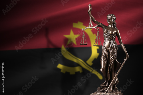 Angola flag with statue of lady justice and judicial scales in dark room. Concept of judgement and punishment, background for jury topics photo