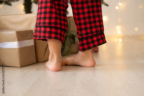 close up kid legs in red Christmas pajama near gift boxes