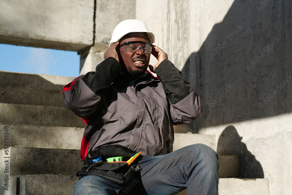 African american worker at project site has headache, he massages his head African american worker at project site has headache, he massages his head