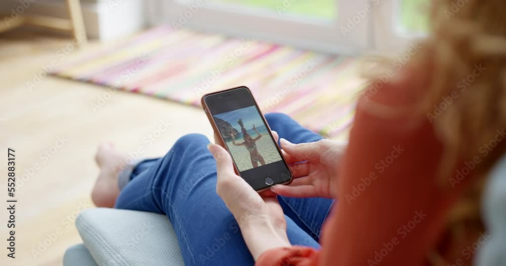 Photos, memories and pictures on a phone in the hands of a woman feeling nostalgic at home from above. Closeup of a female looking at photographs or images of a holiday or vacation in the living room Photos, memories and pictures on a phone in the hands of a woman feeling nostalgic at home from above. Closeup of a female looking at photographs or images of a holiday or vacation in the living room