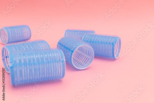 Large blue hair curlers on a bright pink background