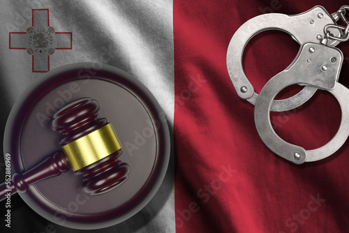 Malta flag with judge mallet and handcuffs in dark room. Concept of criminal and punishment, background for guilty topics photo