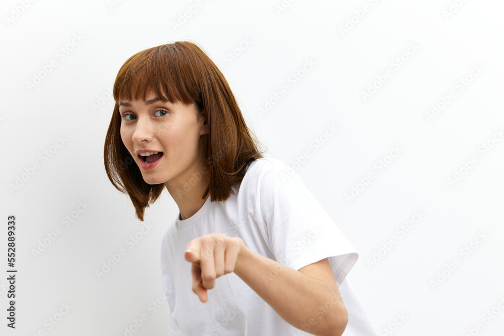 a funny, emotional, beautiful woman smiles broadly and gestures with her fingers towards at camera. standing on the background for inserting an advertising layout a funny, emotional, beautiful woman smiles broadly and gestures with her fingers towards at camera. standing on the background for inserting an advertising layout