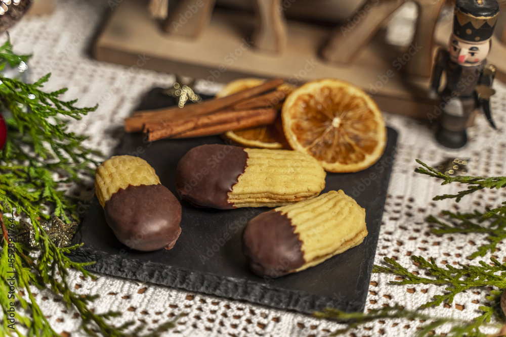 Orangenstäbchen, Plätzchen auf einer Schieferplatte mit weihnachtlicher Dekoration Orangenstäbchen, Plätzchen auf einer Schieferplatte mit weihnachtlicher Dekoration