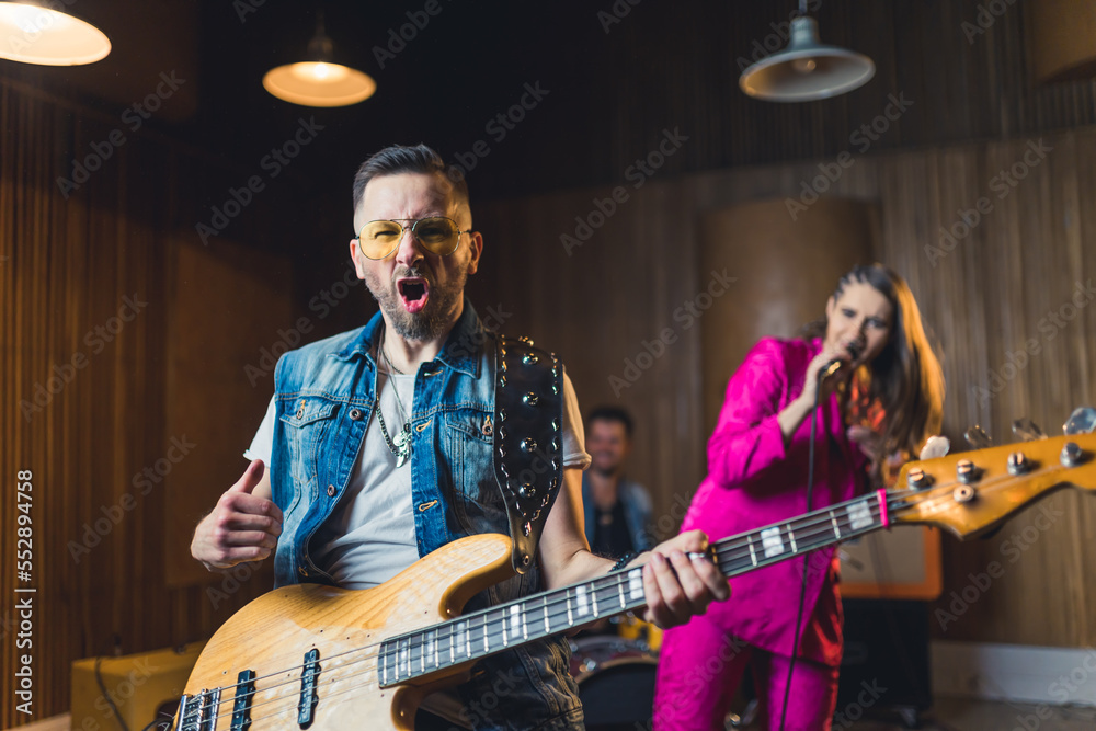 Obraz premium music band performing in a recording studio, a guitarist in front and a singer and a drummer in the background music band concept. High quality photo