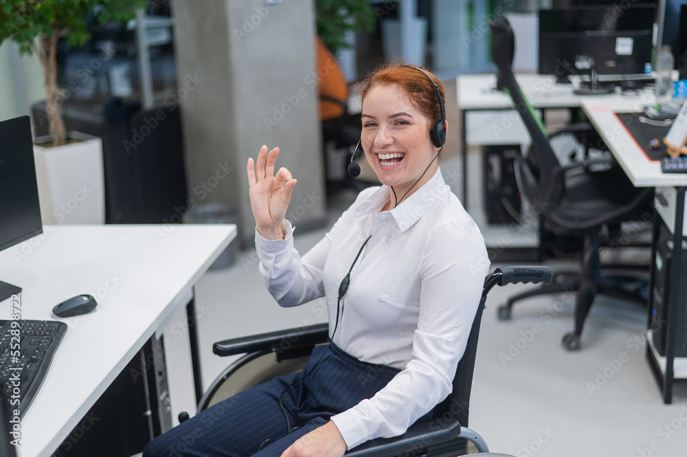 Caucasian woman in wheelchair showing ok sign while sitting in open space office.