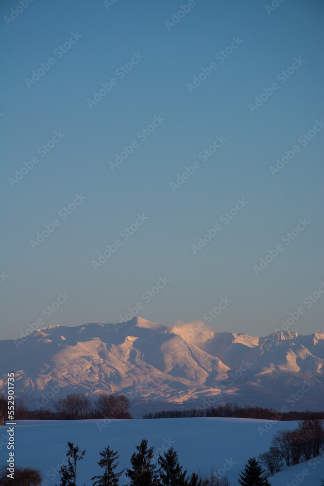 冬の雪原と夕映えの山並み　十勝岳連峰
