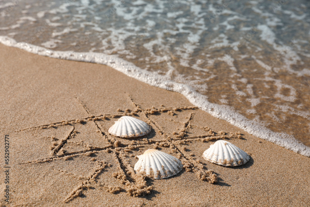 Playing Tic tac toe game with shells on sand near sea Playing Tic tac toe game with shells on sand near sea