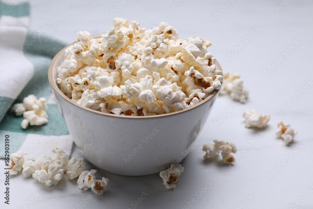Bowl of tasty popcorn on white table, closeup