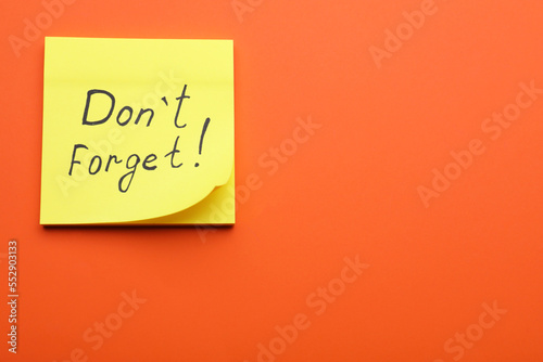 Paper note with phrase Don t Forget on orange background, top view. Space for text