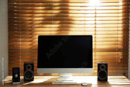 Modern computer with audio speakers and remote on table indoors photo