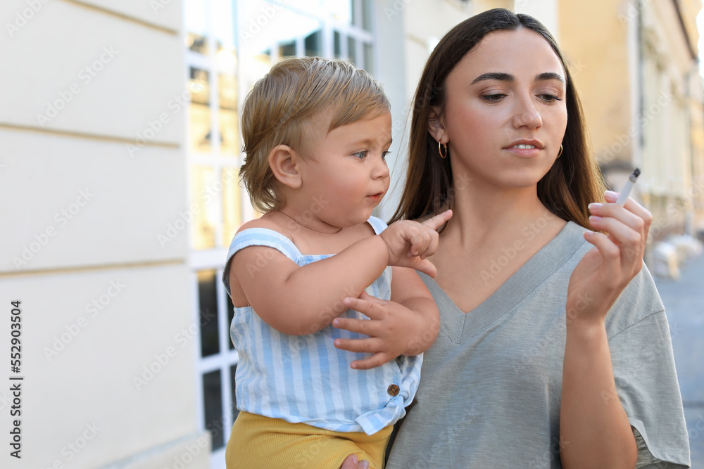 Mother with cigarette and child outdoors. Don't smoke near kids Mother with cigarette and child outdoors. Don't smoke near kids