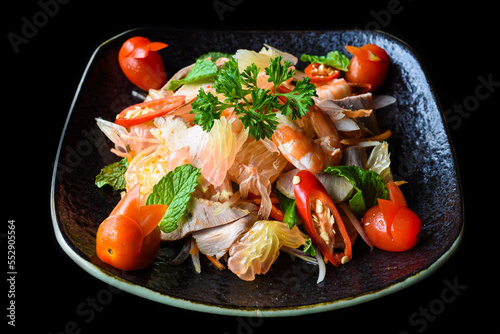 Salad made of shrimps and grapefruit isolated on black background side view