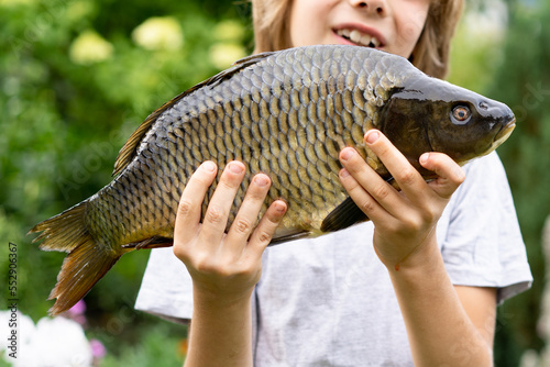 big fish carp in the hands of a boy, fishing with a child, a young fisherman
