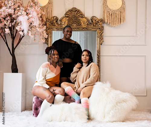 Three Black women sitting on bench and standing in front of mirror