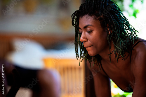 Black woman with dreadlocks spending time practicing yoga meditating and stretching