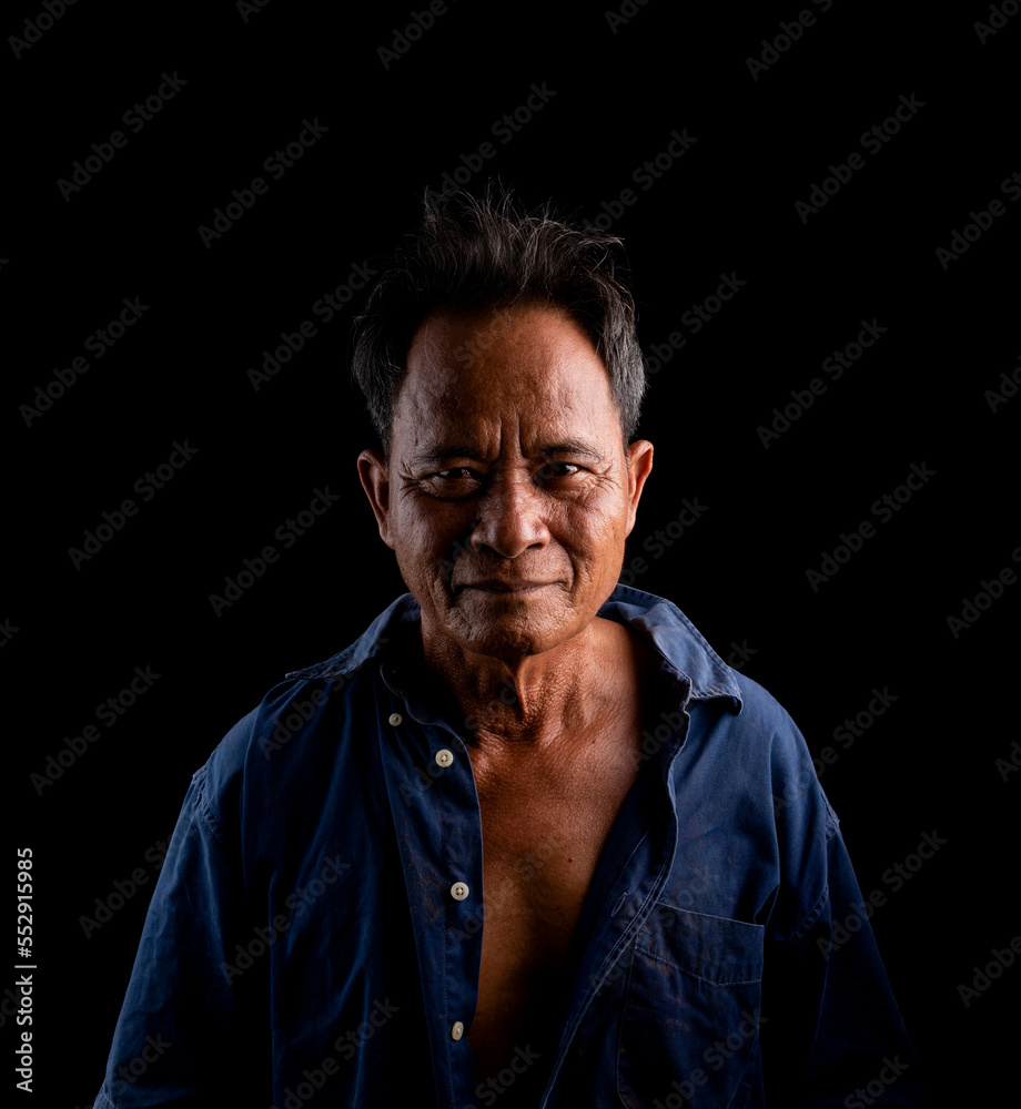 Portrait of an elderly Asian man wearing a blue shirt on a black background.