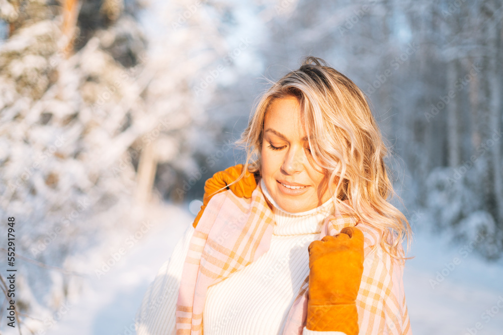 Portrait of smiling blonde woman in winter clothes in snowy winter forest in golden hour Portrait of smiling blonde woman in winter clothes in snowy winter forest in golden hour
