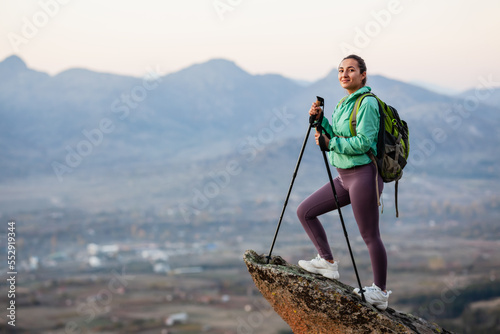 Hiker girl resting on a rock pedestal after long day trekking. Woman enjoying the sunset in nature.