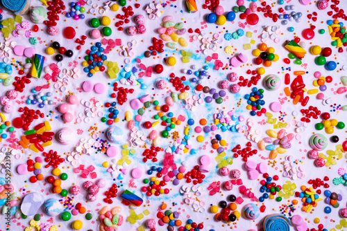 CMulti-colored candy balls on icing sugar table. Candy sweets background made of assorted chocolate coated and jelly beans. Various shaped delicious sugary treats. Holiday festive background.