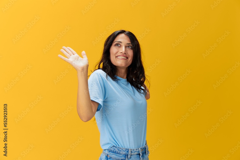 Woman signal smile with teeth emotion portrait in blue t-shirt on yellow background, hands up, surprise, lifestyle, copy space Woman signal smile with teeth emotion portrait in blue t-shirt on yellow background, hands up, surprise, lifestyle, copy space