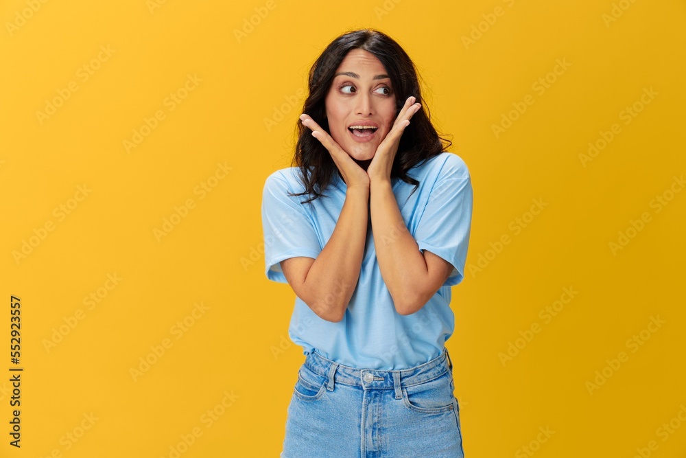 Woman signal smile with teeth emotion portrait in blue t-shirt on yellow background, hands up, surprise, lifestyle, copy space Woman signal smile with teeth emotion portrait in blue t-shirt on yellow background, hands up, surprise, lifestyle, copy space