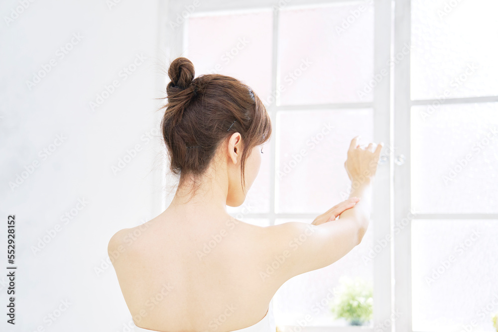 家で腕のケアをする女性の後ろ姿 家で腕のケアをする女性の後ろ姿