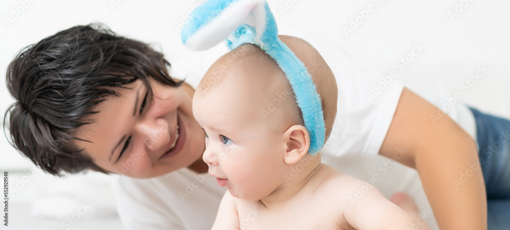 Mother and child with colorful eggs. Mom and baby with bunny ears. Parent and kid play indoors in spring. Family celebrating Easter Mother and child with colorful eggs. Mom and baby with bunny ears. Parent and kid play indoors in spring. Family celebrating Easter