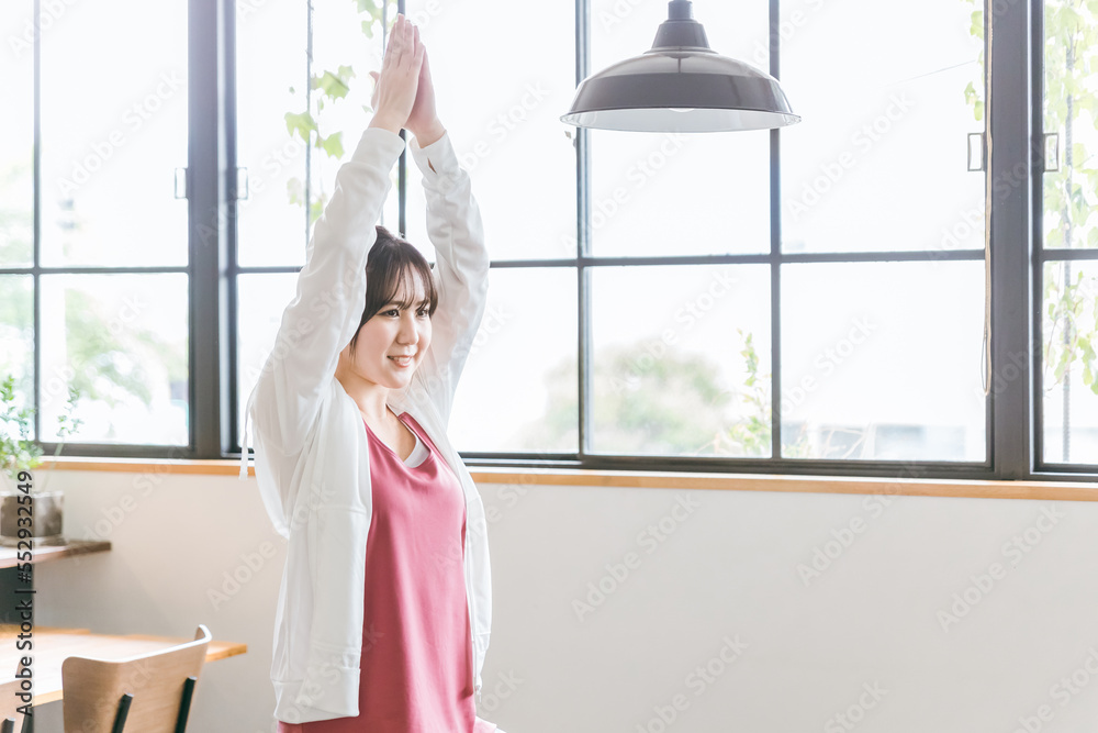 家のリビングでヨガをするアジア人女性
