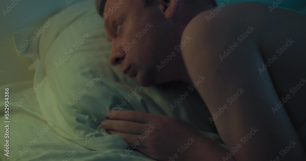 Man goes to sleep after a hard day and switch of night light. Close-up shot Man goes to sleep after a hard day and switch of night light. Close-up shot