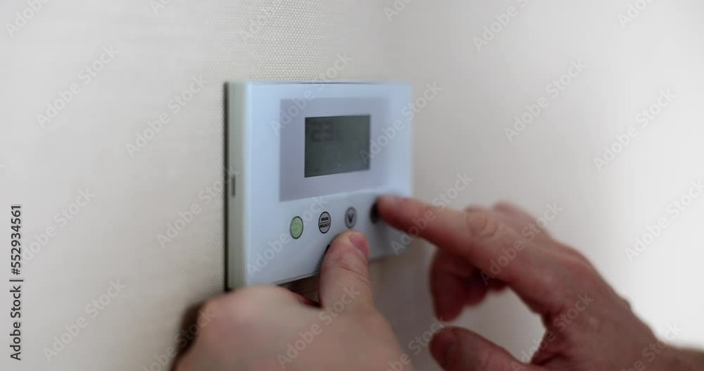 Closeup of person hands adjusting room temperature on digital thermostat Closeup of person hands adjusting room temperature on digital thermostat