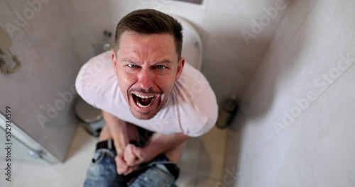 Man suffers from diarrhea constipation hemorrhoids sitting on toilet at home photo
