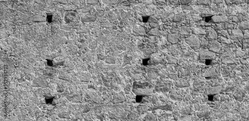 gray monochrone texture of an anciant old castle wall with little windows embrasures photo